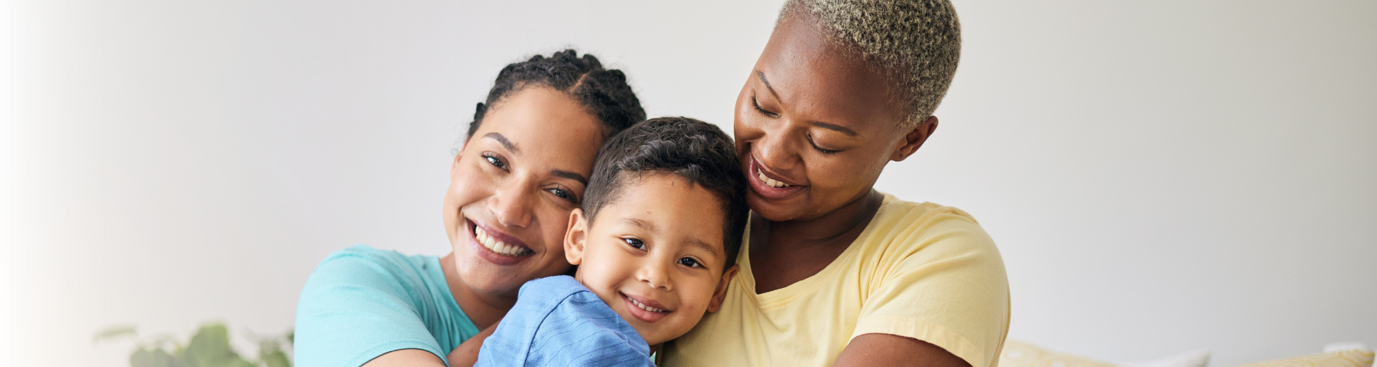 Two adult females hugging a child